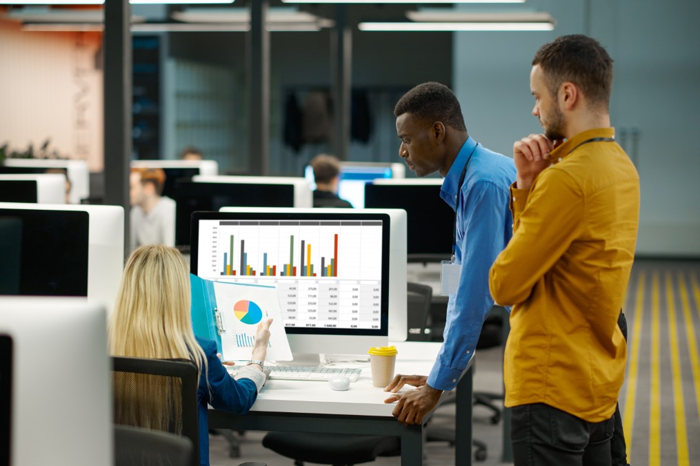 Deux collaborateurs analysant les performances financières d'un projet sur un écran de bureau.
